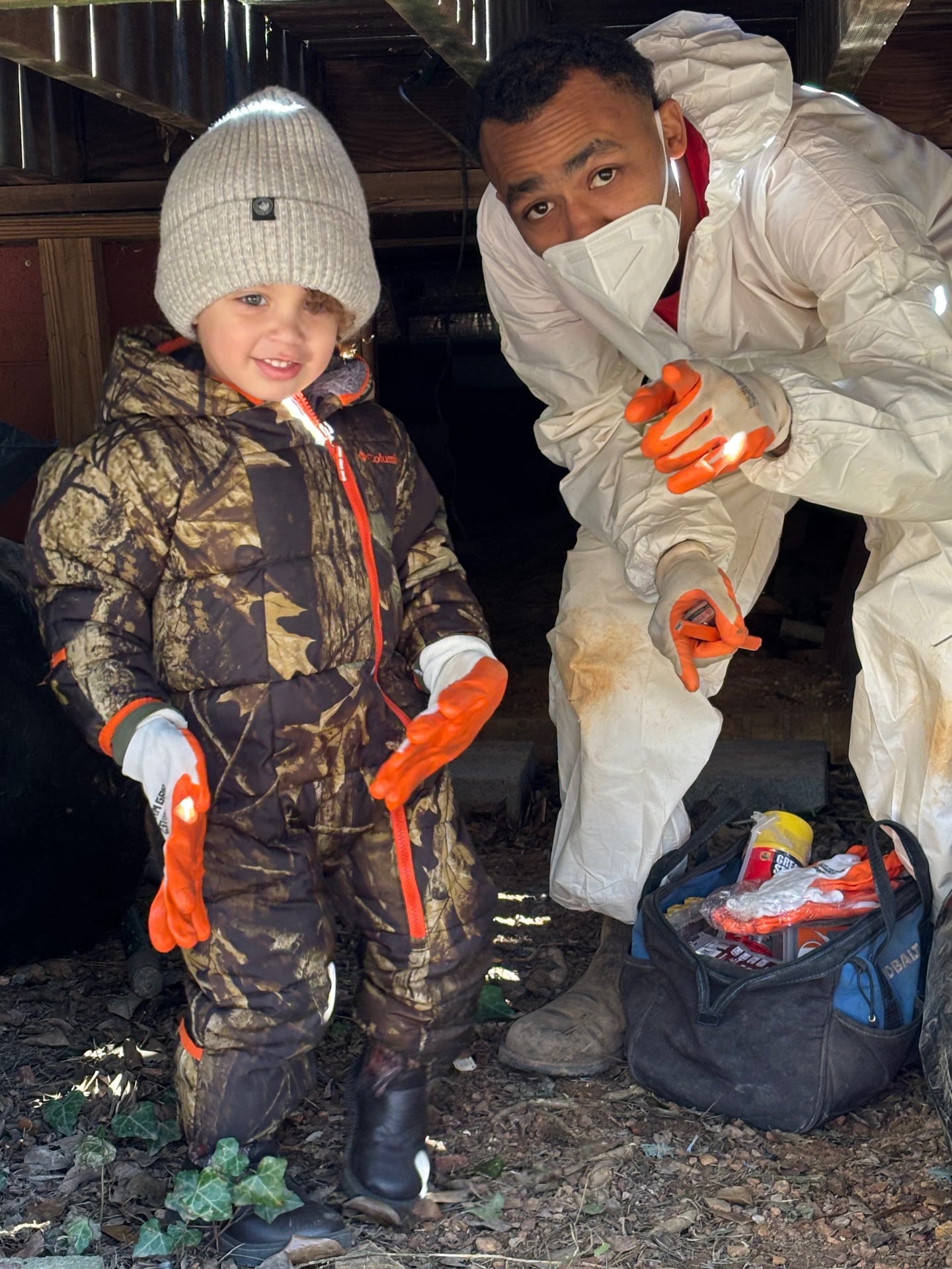 Foundation 1st technician in PPE with young helper at a crawlspace job — family-owned waterproofing in Jemison AL